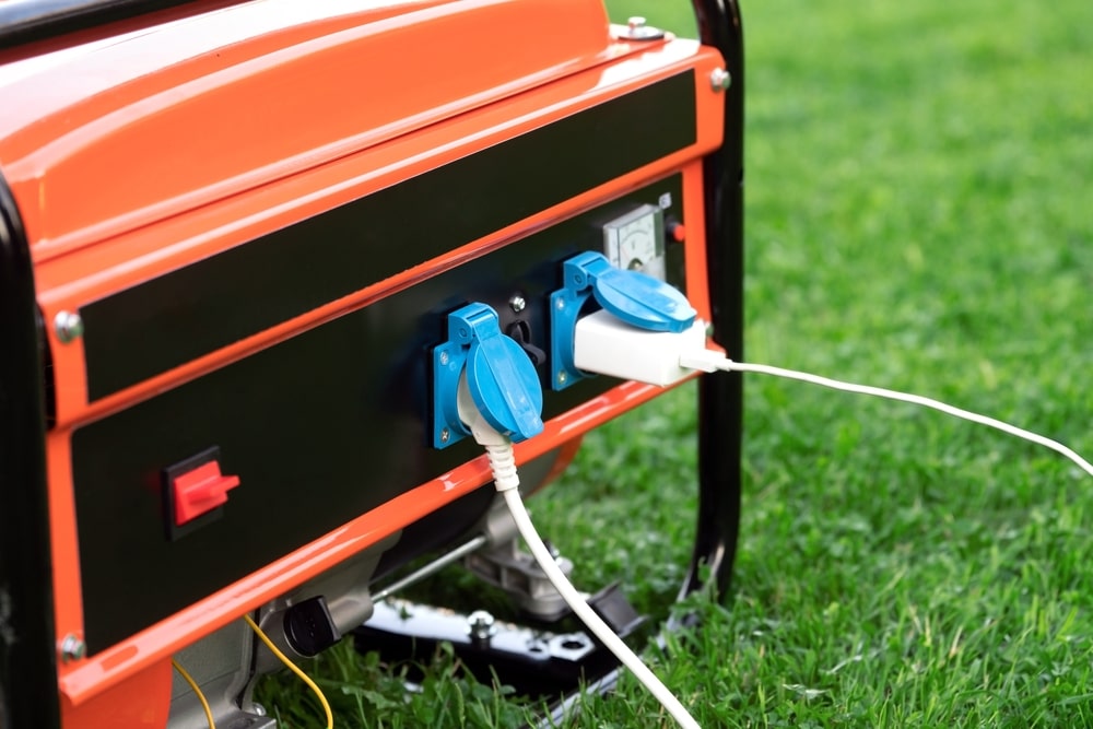 Electric wires connected to an inverted generator on the green grass outdoors - electrician new orleans