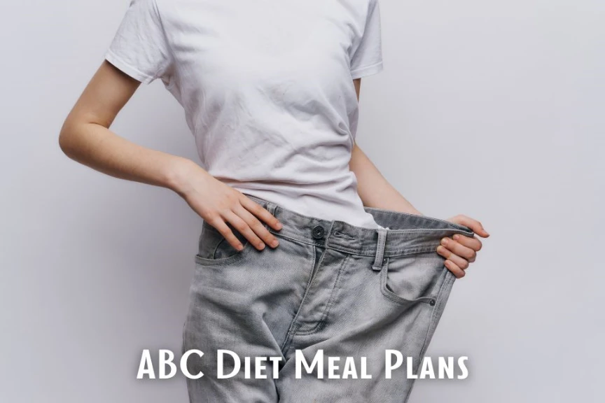 A person wearing a white shirt is showing how loose their jeans are after following an ABC diet meal plan.
