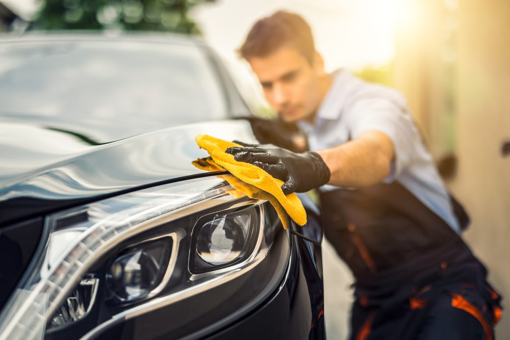 Car detailing - the man holds the microfiber in hand and polishes the car right after a body paint.