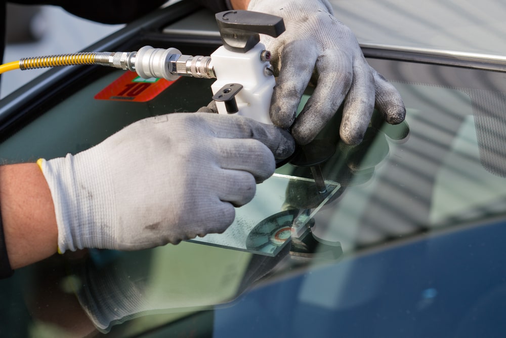 A service technician skillfully mends a significant windshield crack on-site, avoiding the need for replacement. Concept of the auto glass repair in New Orleans.