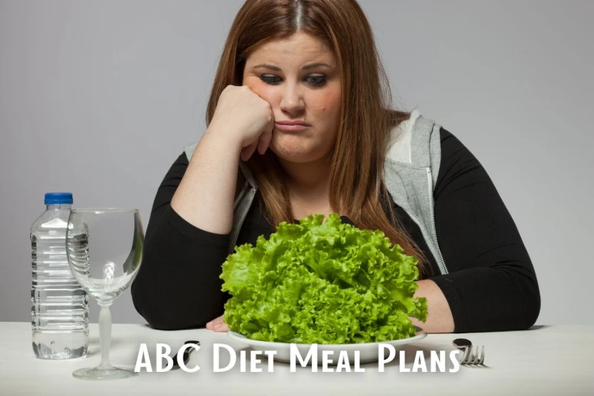 A young woman with a disappointed expression rests her head on her hand as she stares at a plate of lettuce, representing the restrictive nature of ABC diet meal plans.