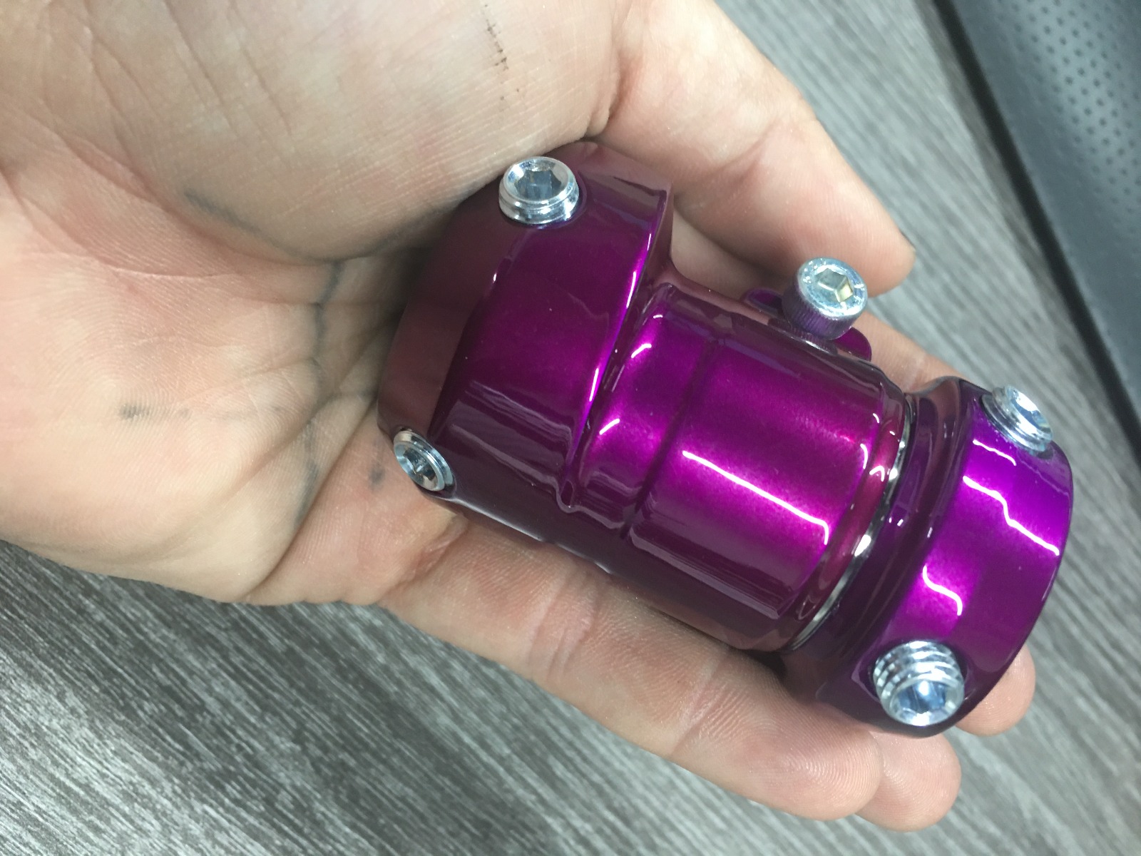 Close-up of a metallic purple powder-coated automotive suspension component held. Kenner automotive